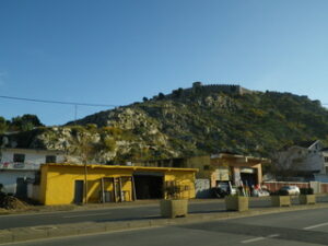 岩山の手前にある黄色い壁の建物