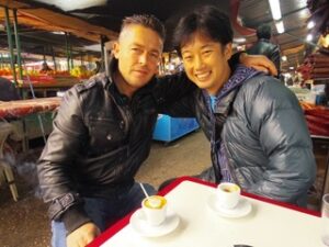お茶を飲んで肩を組む男性二人
